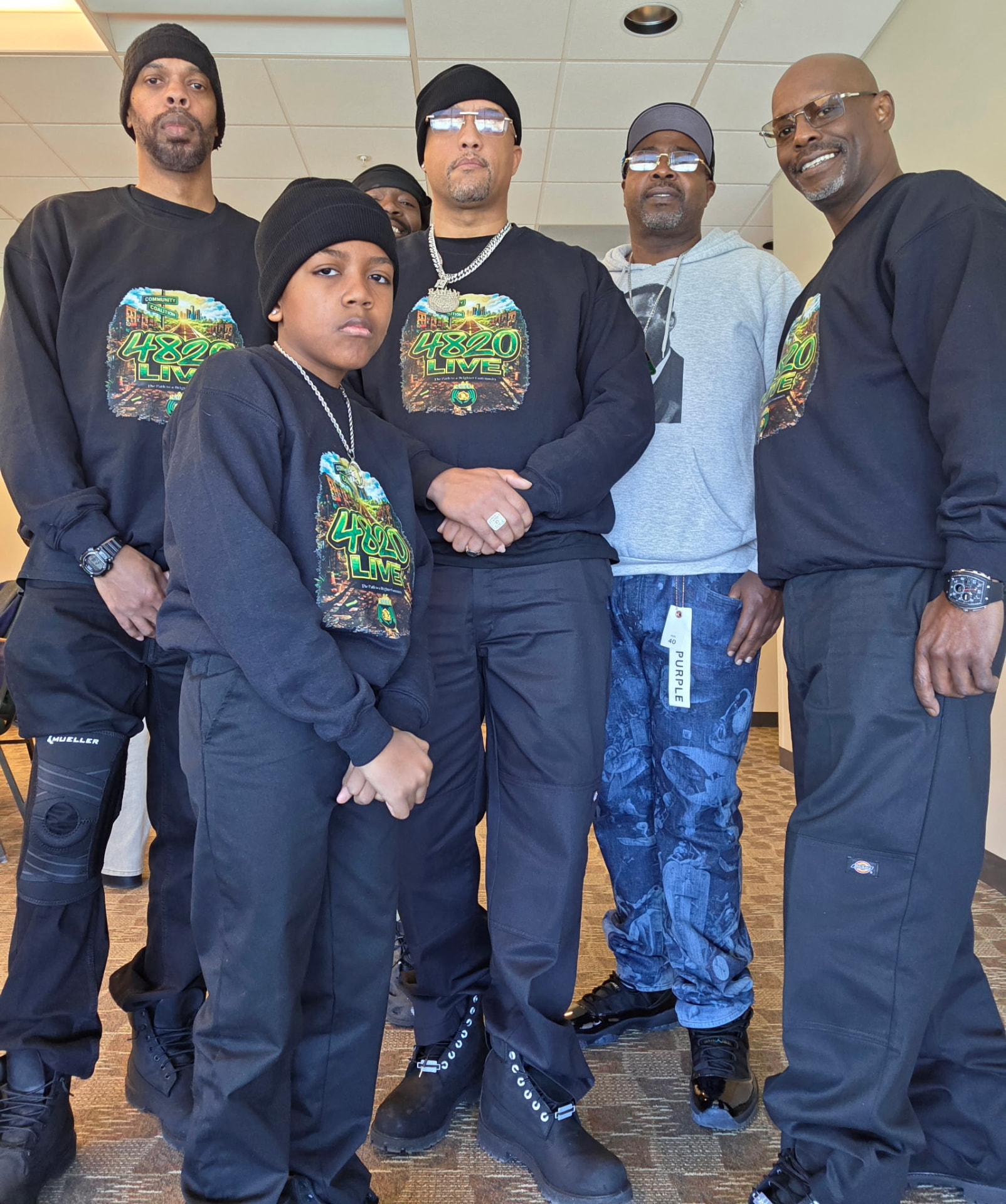 Men and boys in matching 4820 Live shirts standing together